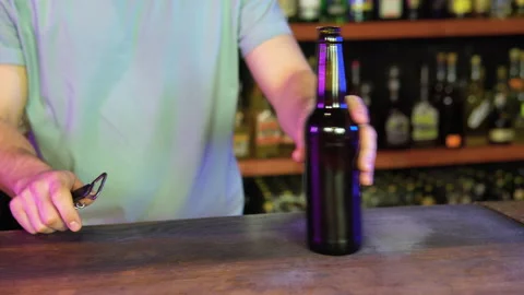 Barman opens bottle of beer in interior of modern pub. Serve customers at bar Stock Footage 231675803