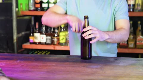 Barman opens two bottles of beer in interior of modern pub. Serve customers at Stock Footage 231677509