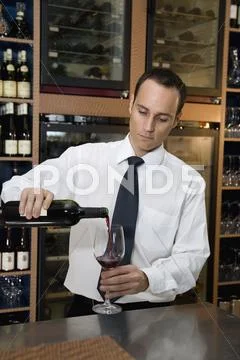 A barman pouring a glass of red wine Stock Photos