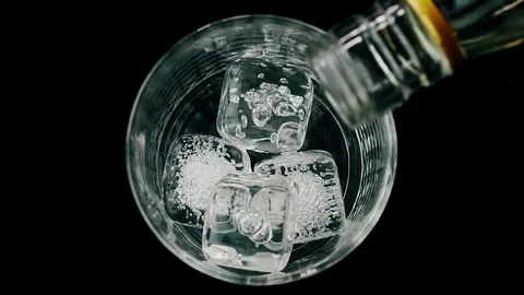 Barman pouring whiskey with ice cubes in the glass on wood table, view top Video stock 70894583