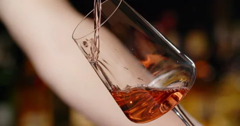 Barman pours rose wine to the wine glass at the bar counter in slow motion, 4k Stock Footage 157443056