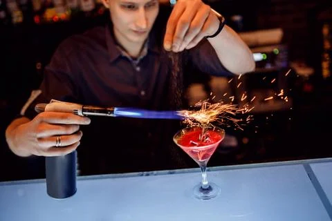 Barman prepares red cocktail with cinnamon ice rosemary in transparent glass on 스톡 사진