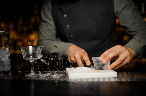 Barman preparing a large rectangular piece of ice n the plastic desk Stockfoto's