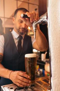 Barman serving beer in a pub. Stock Photos