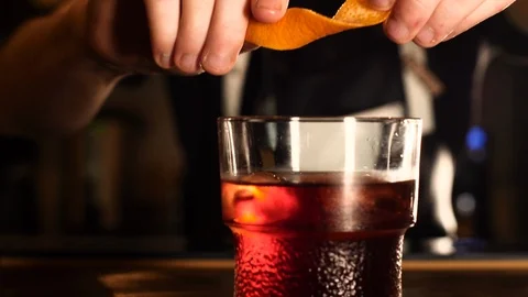 Barman Squeezing Orange Peel on Negroni Cocktail Stock Footage 95192053