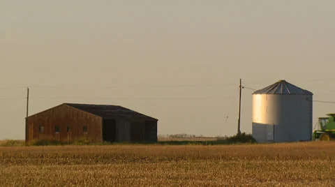 Barn, silo, and passing tractor on farm field Stock Footage 32936850