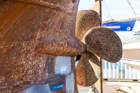Barnacle covered propeller on rusty boat hull 库存照片
