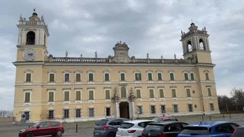 Baroque palace facade emerging slowly, parking area framing historic Reggia di 動画素材 306677276