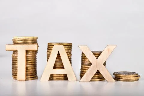 Bars stacked from coins on a white table. TAX lettering with wooden letters b 스톡 사진