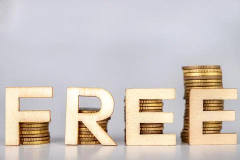 Bars stacked from coins on a white table. FREE lettering with wooden letters  스톡 사진
