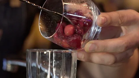 Bartender adding cranberry and raspberries in alcoholic coctail. Slow motion Stock Footage 96147421