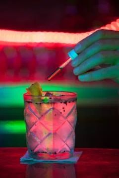 Bartender adding drops into a cocktail with a dispenser in a bar Stock Photos