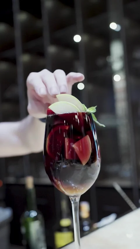Bartender Adding Fresh Fruit Garnish to Red Wine Sangria Cocktail. Close-up.. Stock Footage 333915142