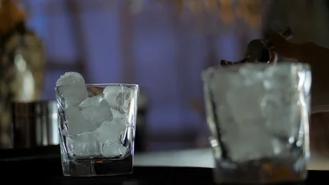 Bartender adding an ice cubes to the empty cocktail glasses on the bar counter Stock Footage 124612048