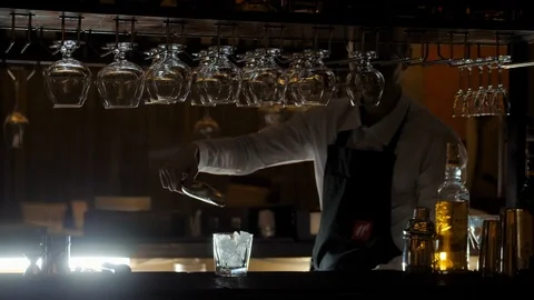 Bartender adding an ice cubes to the empty cocktail glasses on the bar counter Video stock 124619756