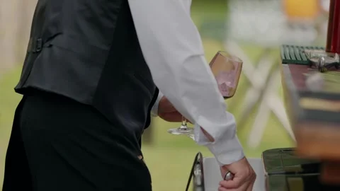 Bartender adding ice cubes into two wine glasses at an outdoor event Stock Footage 296582726