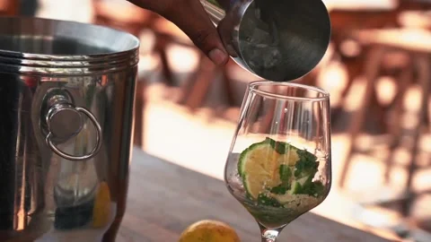 Bartender adding ice to a glass to make a passion fruit mojito cocktail Stock Footage 230080290