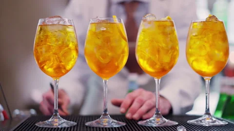 Bartender adding orange fruit pieces to Aperol Spritz cocktail at the bar Stock Footage 344763927