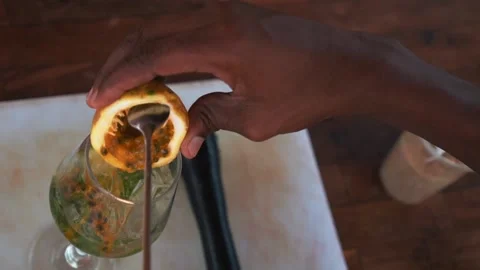 Bartender adding passion fruit juice to a glass, making a mojito cocktail Stock Footage 230080340