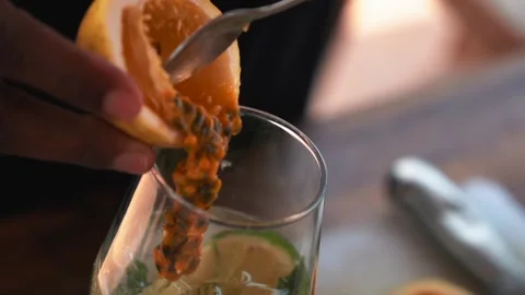 Bartender adding passion fruit juice to a glass, making a mojito cocktail Stock Footage 230080360
