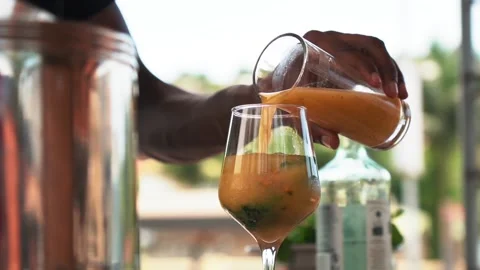 Bartender adding passion fruit juice to a glass, making a mojito cocktail Stock Footage 230080369