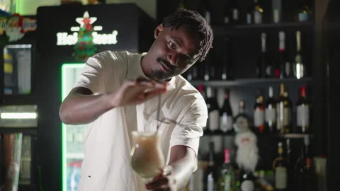 Bartender adding straw to cocktail glass with illuminated bar shelves Stock-Footage 317199183