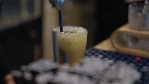 Bartender adding straws to frothy green cocktail close up Stock Footage 328142821