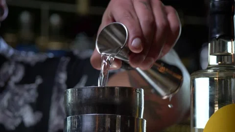 Bartender adds gin into a metal shaker for cocktail mixing 4K 60fps Stock Footage 196821384