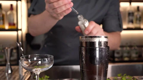 Bartender adds parfume aromatic drops in a cocktail shaker on a bar counter. Video stock 209524283