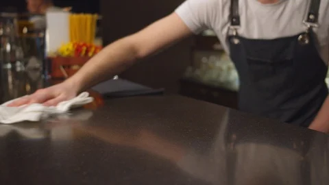 Bartender in the apron wipes bar counter with a rag, close up Stock Footage 123673611