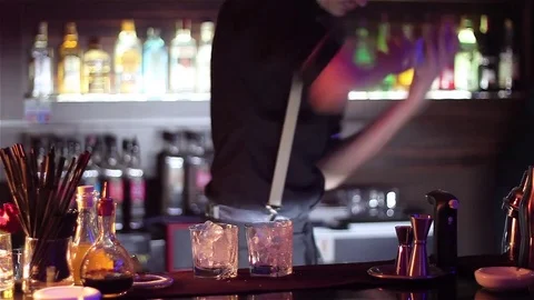 Bartender, barman is making delicious cocktail at bar counter using ice and swee Stock Footage 76473017