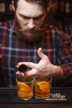 The bartender with the beard pours a drink at the bar. Stock Photos
