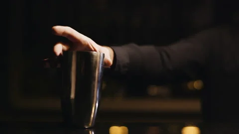 Bartender in the black shirt puts the lid on the cocktail shaker Stock Footage
