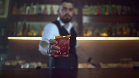 Bartender bring and put on the bar counter an orange martini, Stock Footage 158097084