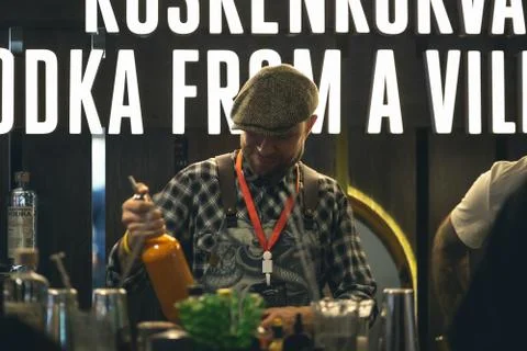 The bartender in a cap looks at a bottle of orange liquor Stock Photos