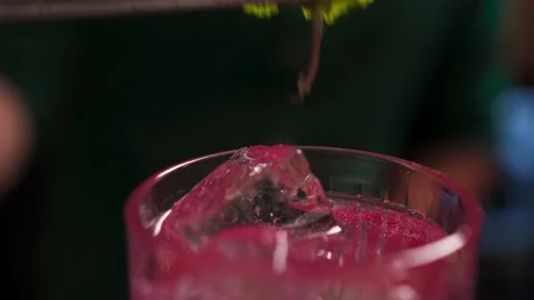 The bartender carefully puts mint from tweezers on the pink drink with ice Stock Footage 164559053