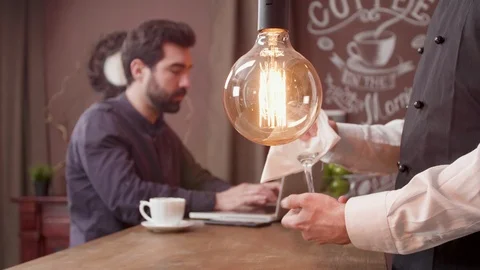 Bartender cleaning a glass while a customer works at the bar counter Stock Footage 106702609