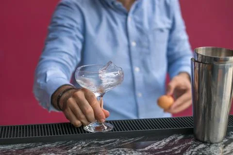 Bartender cools the glass with ice before making a cocktail. Close up photo Stock Photos