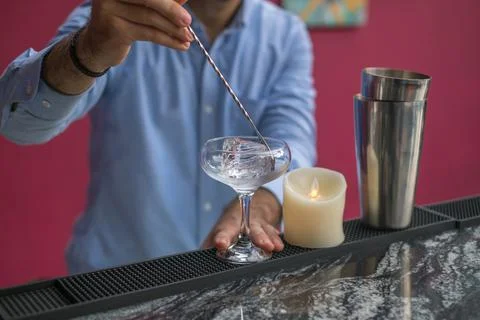 Bartender cools the glass with ice before making a cocktail. Close up photo Stock Photos