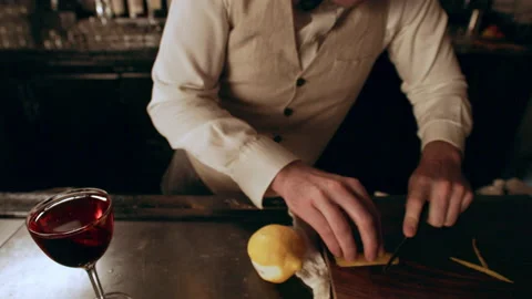 Bartender cutting a thin slice of a lemon peel to garnish a Negroni cocktail. Me Stock Footage 199461166