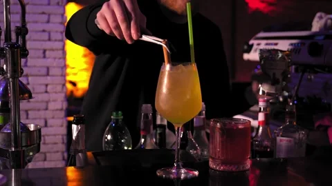 Bartender decorating cocktail with cinnamon stick and straw on bar counter. Stock Footage 269560702