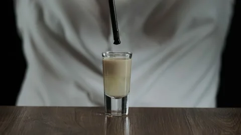 The bartender drips a drop of grenadine syrup from a drinking straw Stock Footage 132742651