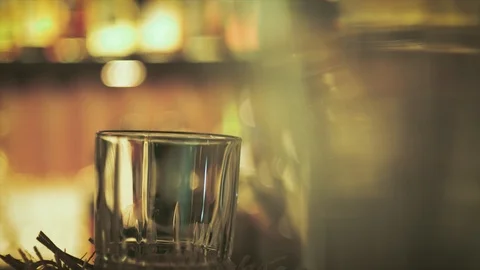 Bartender dropping ice cubes in cocktail drink glass in bar Stock Footage 103813527