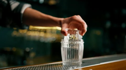 The bartender effectively puts an ice cube in a glass at the bar The initial Stock Footage 240443436
