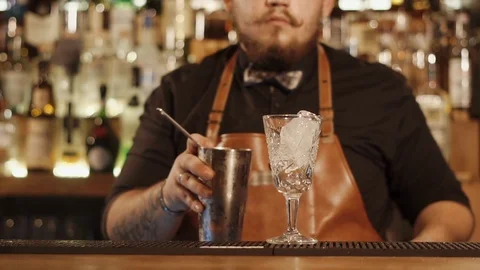 Bartender is filtering mixed drink into glass for serving, close-up of his hands Stock Footage 88738060