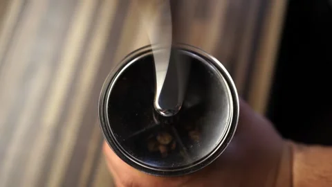 Bartender grinds coffee beans in a manual coffee grinder by quickly turning the Stock Footage 281925474