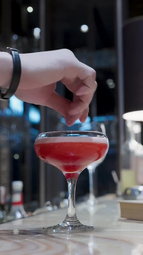 Bartender Hand Decorating Red Cocktail in Coupe Glass. Close-up of a barten.. Stock Footage 333915083