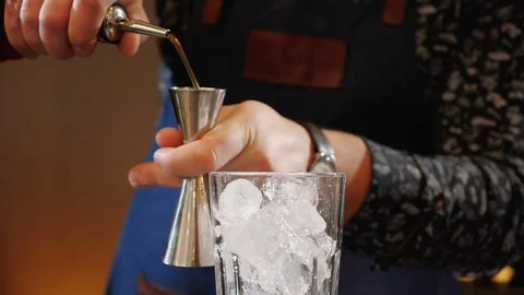 Bartender hands making a cocktail using a jigger to measure ingredients Video stock 105842468
