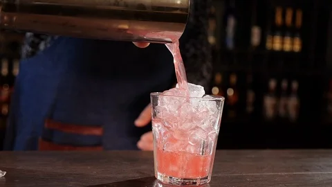 Bartender hands pouring the mix from a shaker cup in a glass - close up Видео 105720859