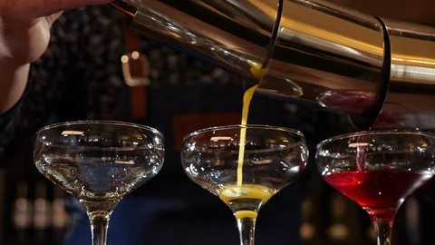 Bartender hands pouring three colored cocktails simultaneously - close up Video stock 105295896